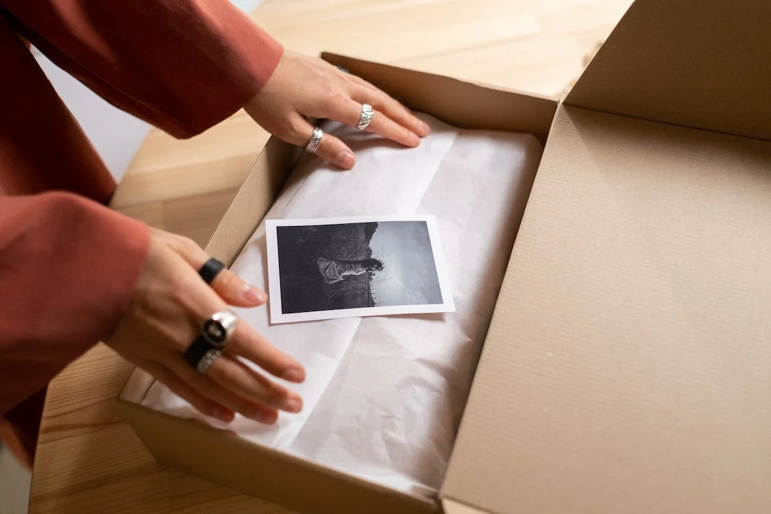 A woman putting a polaroid picture in a box.